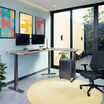 reclaimed wood finish l shape electric standing desk in a raised position in the corner of a workspace